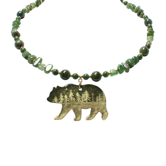 Close-up of hand-painted bear pendant with night forest scene and twinkling stars